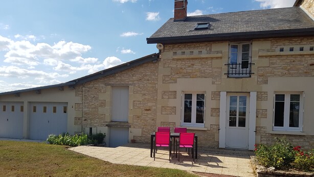 A stone building with a flat roof, a balcony, and a small garden area with chairs and plants. - In the countryside for Prof et Voyageur (Moncontour)
