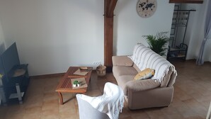 A living room with a sofa, a coffee table, a chair, a world map clock, and a hanging rack. - In the countryside for Prof et Voyageur (Moncontour)