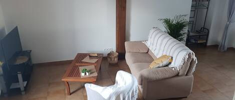 A living room with a sofa, a coffee table, a chair, a world map clock, and a hanging rack.
