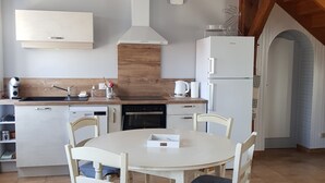 A modern kitchen with white cabinetry, a central island, and a dining table with chairs. - In the countryside for Prof et Voyageur (Moncontour)