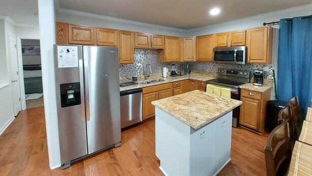 A modern kitchen with wooden cabinets, stainless steel appliances, and a central island.