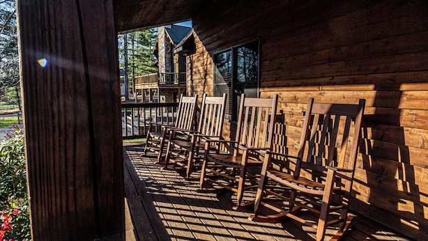 Eine Holzterrasse mit Schaukelstühlen und einem hölzernen Häuschen.