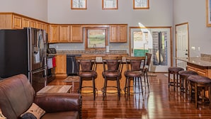 Eine geräumige Küche mit Holzausstattung, einem Kühlschrank und einer Bar mit Hockern.
