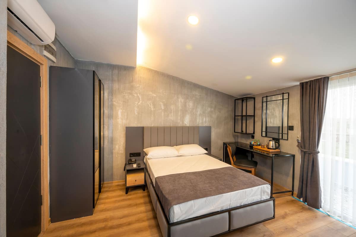 Una habitación de hotel moderna con cama, mesita de noche y escritorio con silla.