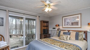 A bedroom with a large bed, a ceiling fan, a TV, and a sliding glass door leading to a deck. - Donnas Choice by Taylor Made Deep Creek (McHenry)