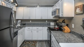 A kitchen with white cabinets, granite countertops, a refrigerator, a microwave, and a coffee maker. - Donnas Choice by Taylor Made Deep Creek (McHenry)