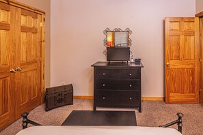 A bedroom with a bed, a dresser, a mirror, and two wooden doors. - Donovan's Dacha by Taylor Made Deep Creek (McHenry)