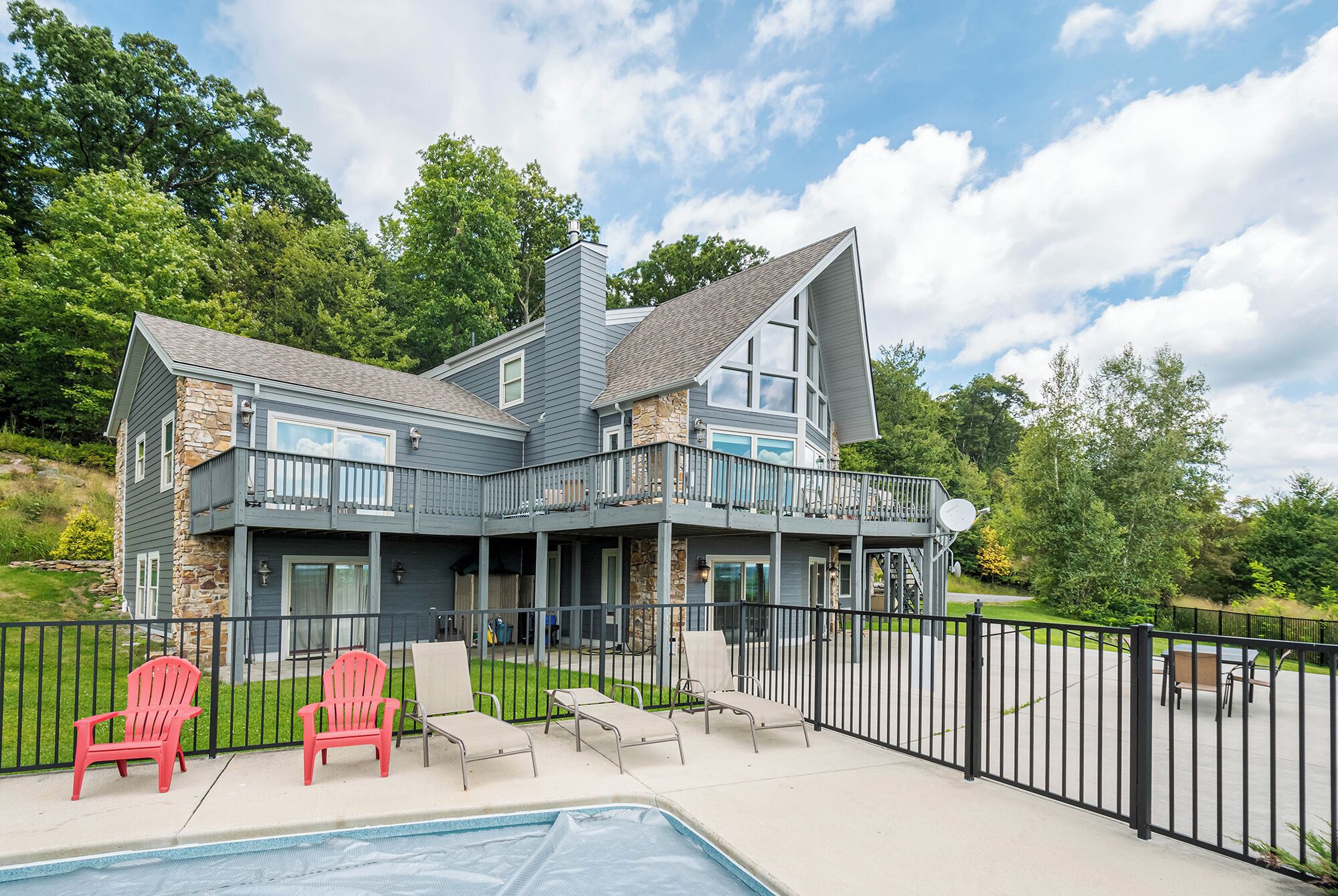 A two-story house with a stone facade, a balcony, and a swimming pool.