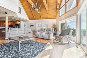 A spacious living area with a high ceiling, large windows, and a view of the outdoors. - Dream Big by Taylor Made Deep Creek (Swanton)