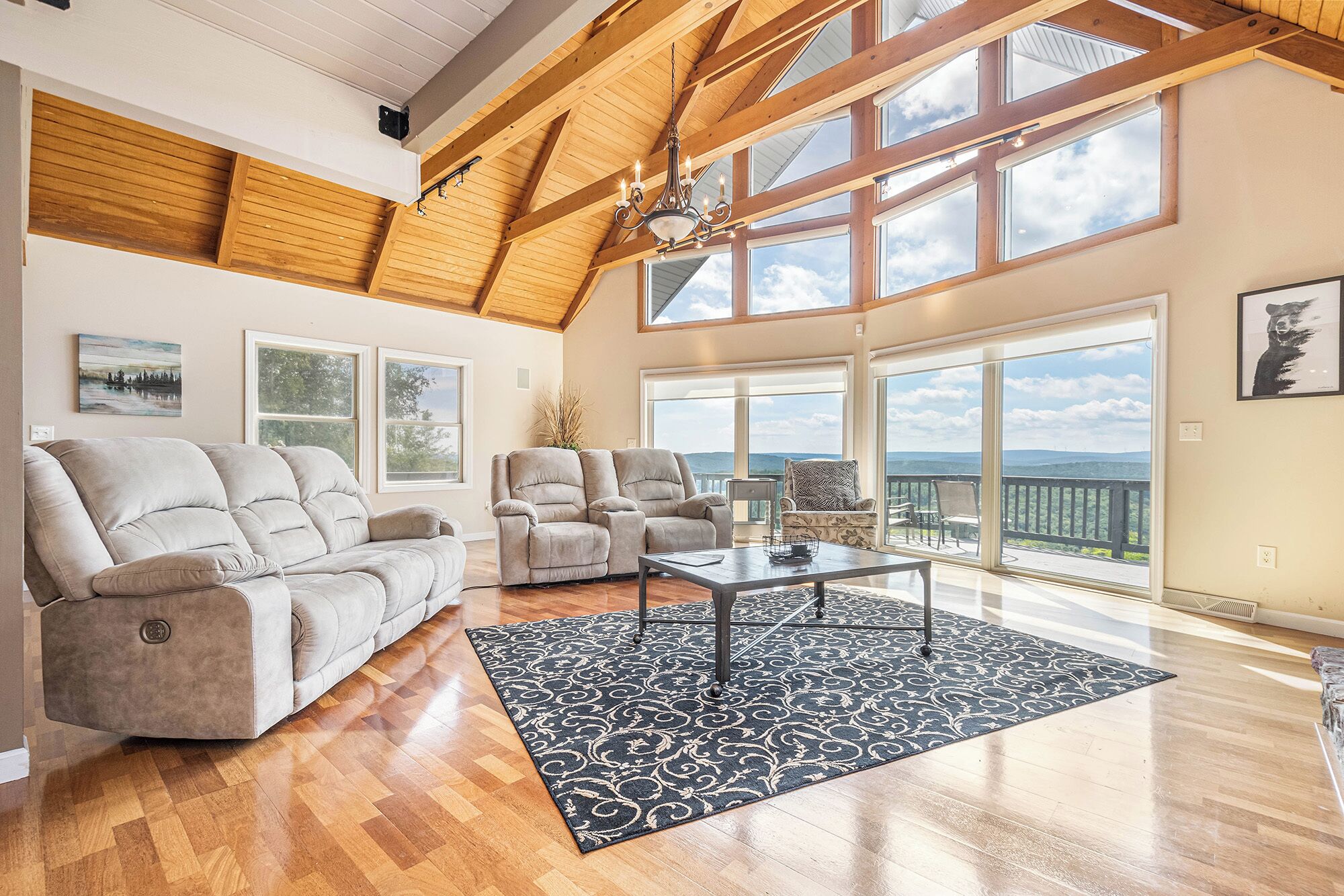 A spacious living room with a high ceiling, large windows, and a view of the outdoors.