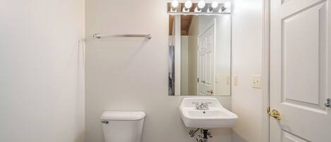 Un baño con inodoro, lavamanos, espejo y cortina de ducha.
