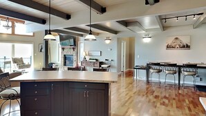 Una cocina amplia con una isla grande, muebles oscuros e iluminación colgante.