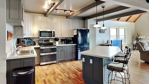 Una cocina moderna con una isla central, electrodomésticos de acero inoxidable y suelo de madera en espiga.
