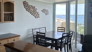 A dining area with a wooden table and chairs, a kitchen with a wooden countertop, and a view of the sea through large windows. - Paradise in Pensacola Beach/Gulf of Mexico (Pensacola Beach)