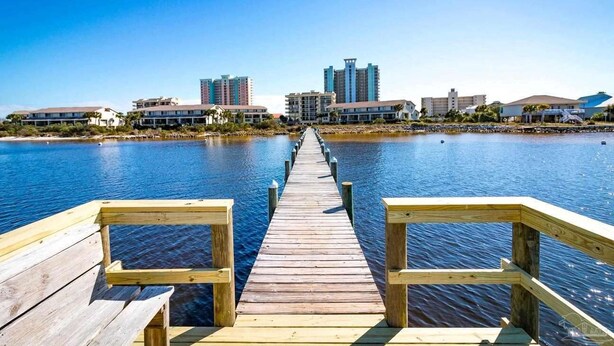 A wooden pier leading to a waterfront area with buildings in the background. - Paradise in Pensacola Beach/Gulf of Mexico (Pensacola Beach)
