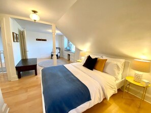 Una camera da letto con un letto grande, una scrivania e una sedia. Si trova anche un tavolino e una lampada.