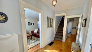 A hallway with wooden flooring, a red leather sofa, and a staircase leading to another room.