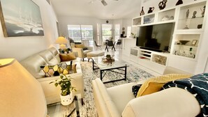 A modern living room with a sofa, coffee table, and TV stand. - 5 Miles to the beach, family home, saltwater pool, pickleball & tennis courts (Naples)
