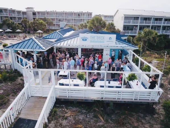A decked boat with a restaurant named "The Deck" surrounded by people. - Oceanfront Luxury ,Heated Pool , Amazing View located in Beachside Colony Resort (Tybee Island)