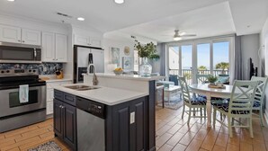 Una cocina moderna con una isla central, electrodomésticos de acero inoxidable y un área de comedor con vistas.