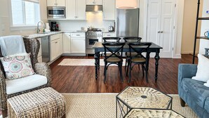 Una cucina moderna con mobili bianchi, elettrodomestici in acciaio inossidabile e una zona pranzo con tavolo e sedie in legno scuro.