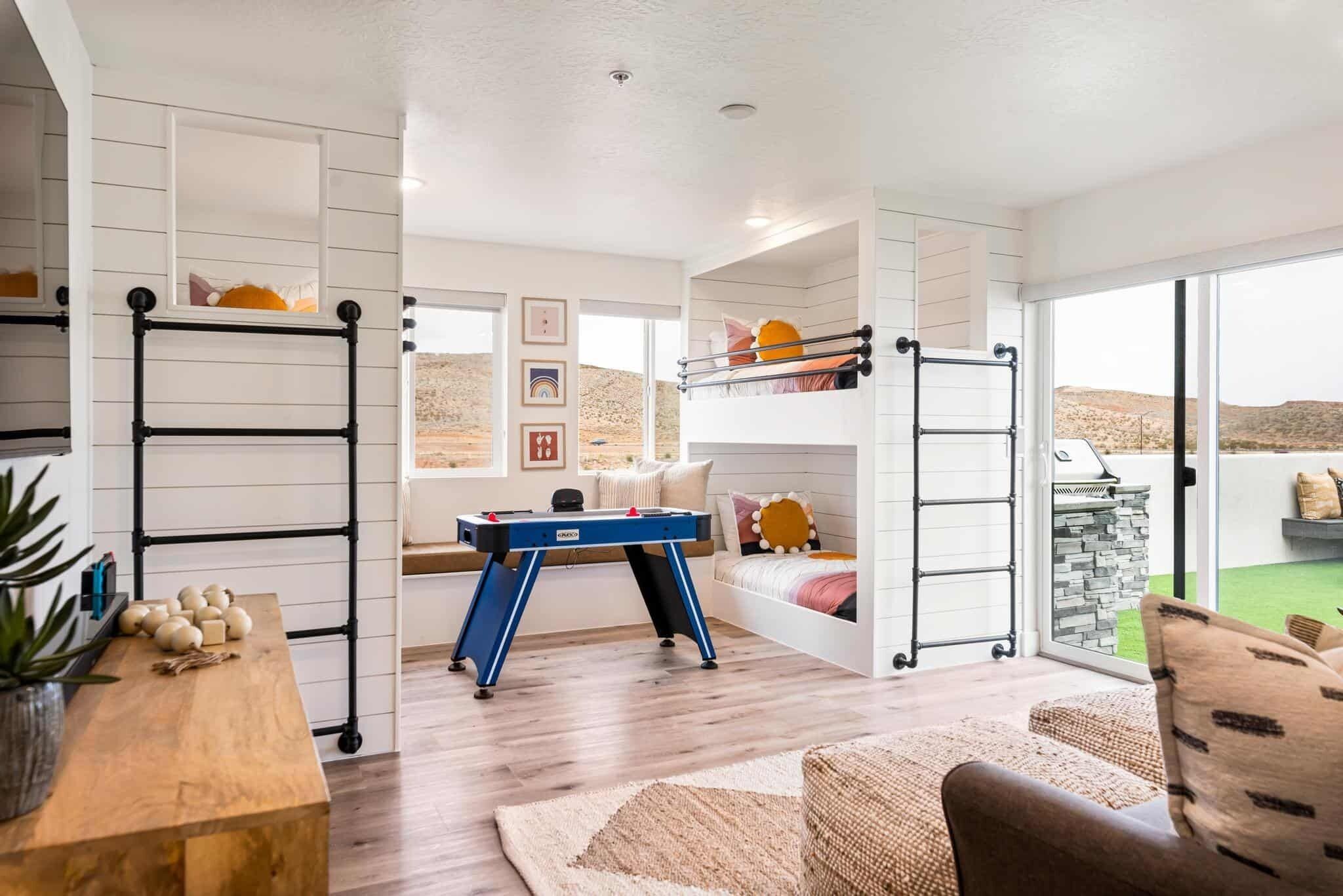 A spacious room with a bunk bed, a desk with a computer, and a window with a view of the desert.