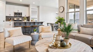 Uma sala de estar moderna com uma mesa de centro redonda, dois sofás e um espaço de refeições com banquetas.