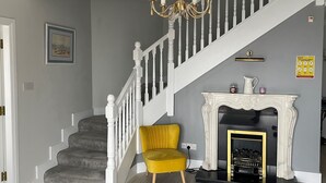 Eine Treppe mit weißen Balustraden, ein gelber Sessel und ein Kamin mit goldener Verkleidung.