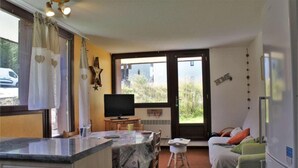 A room with a bed, a desk, a television, and a window with a view of greenery. - 250m from resort center, 3rd floor, terrace, tv, ski locker, 45m², Risoul (Risoul)