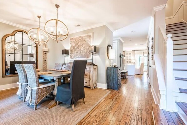 A dining area with a wooden table, wicker chairs, and a chandelier.