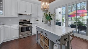 A kitchen with white cabinets, a stainless steel stove, and a large window with a view of the outdoors.