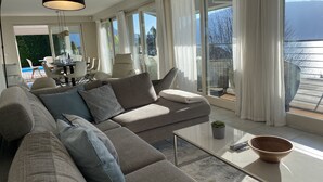 Ett modernt vardagsrum med en soffa, ett soffbord och utsikt över omgivningen.