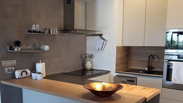Une cuisine moderne dotée d’un îlot central, d’appareils électroménagers intégrés et de nombreux rangements.