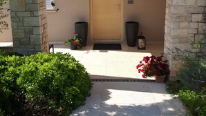 Une entrée avec un mur en pierre, une porte en bois et des plantes en pot.