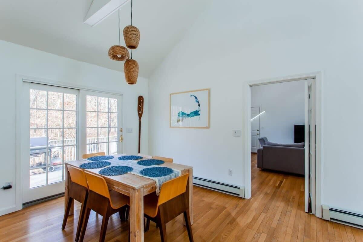 A dining area with a wooden table, chairs, and woven pendant lights.