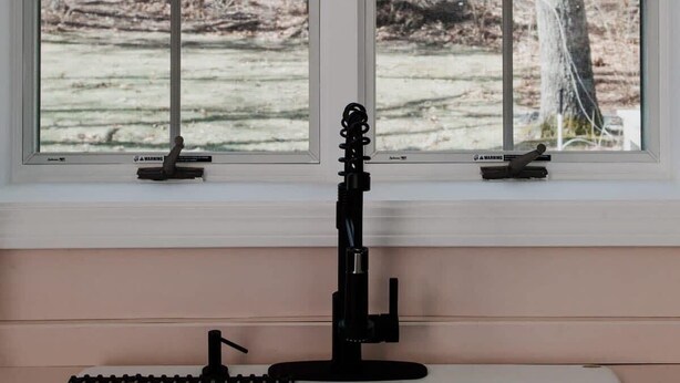 A room with a large window, a black stand with a camera, and a woven pendant light. - Modern Family Getaway In Harwich (Harwich)