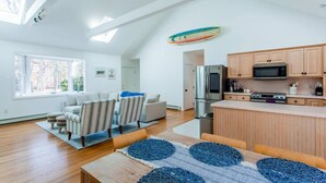 A spacious living area with a sofa, chairs, a dining table, and a kitchen with wooden cabinets and appliances. - Modern Family Getaway In Harwich (Harwich)