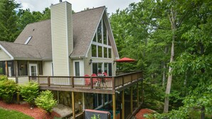 A house with a large deck, a covered patio, and a view of a forest. - Dreamers Inn by Taylor Made Deep Creek (Swanton)