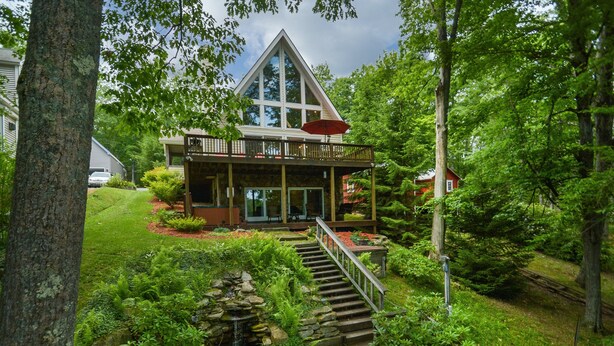 A house with a wooden deck, a stone staircase, and a pond. - Dreamers Inn by Taylor Made Deep Creek (Swanton)