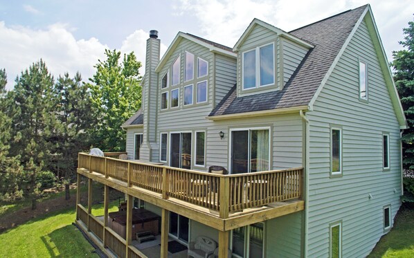 A two-story house with a balcony, large windows, and a chimney. - Duck Cove at Wisp by Taylor Made Deep Creek (McHenry)