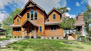 A large, two-story log cabin with a prominent front porch and a stone chimney. - Eagle on 7 by Taylor Made Deep Creek (McHenry)