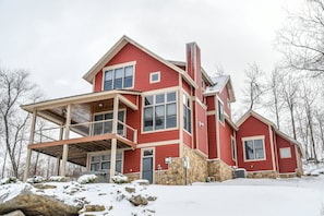 A red two-story house with a balcony, stone foundation, and a chimney. - Eagle's Rest by Taylor Made Deep Creek (McHenry)
