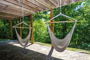 Two hammocks hanging under a wooden pergola with a stone patio, surrounded by lush greenery. - Family Sanity by Taylor Made Deep Creek (McHenry)
