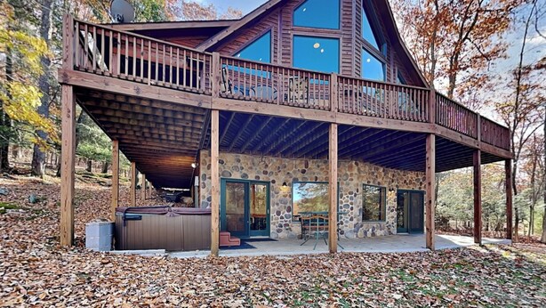 A modern cabin with a stone exterior, a wooden deck, and a large glass window. - Fir Reel by Taylor Made Deep Creek (Oakland)
