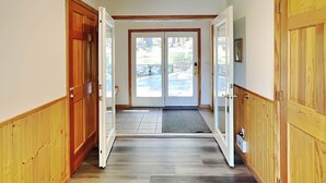 A hallway with wooden doors and a view of a landscaped area outside. - Fir Reel by Taylor Made Deep Creek (Oakland)