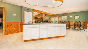 Una cocina con una isla central, paneles de madera y una chimenea de piedra.