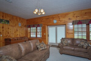 A cozy room with wooden walls, a brown leather couch, a brown leather sofa, and a foosball table.