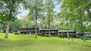 A two-story building with a balcony on the upper level, surrounded by lush greenery. - Four Hooppole South G6 by Taylor Made Deep Creek (Oakland)