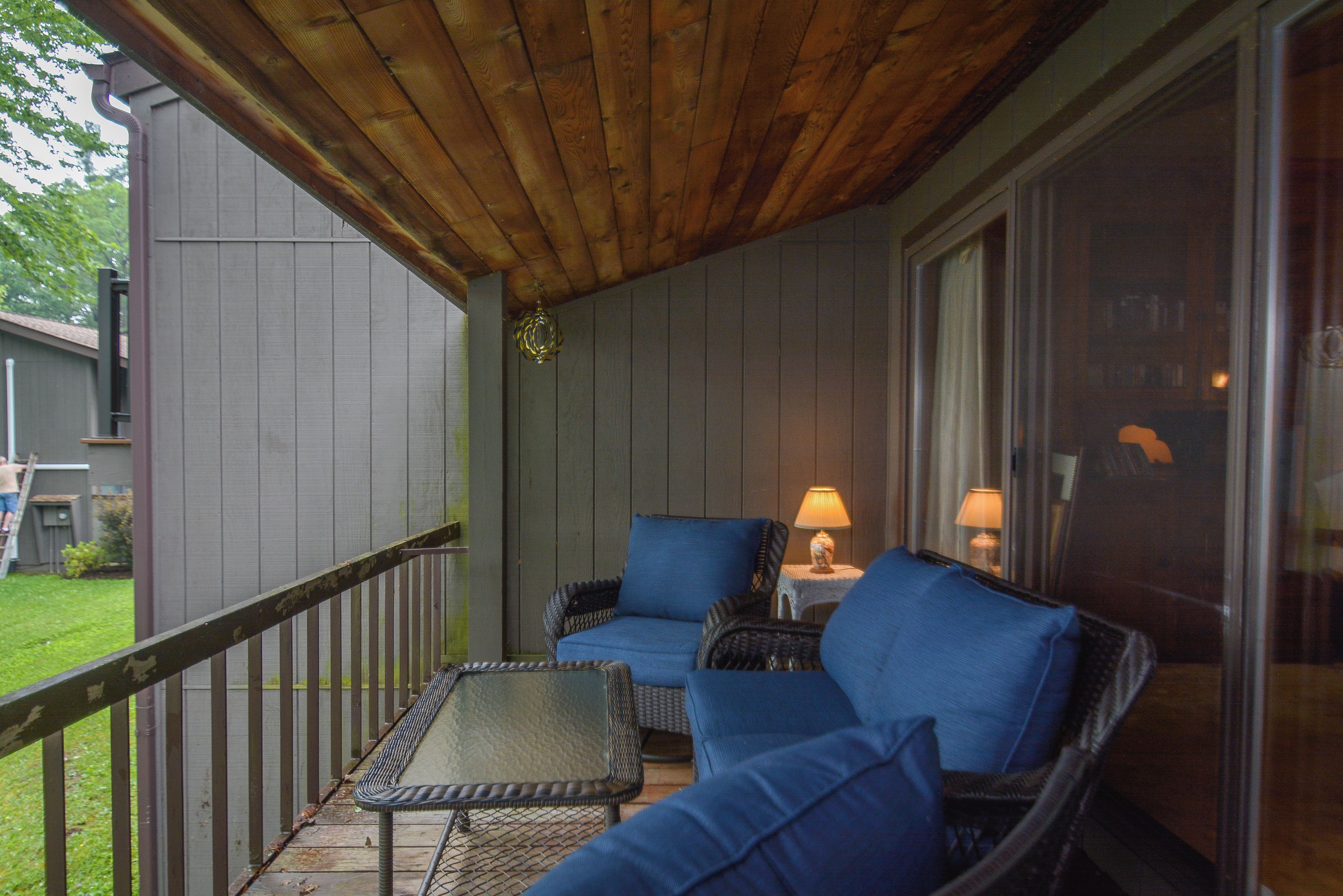 A covered porch with wicker furniture and two table lamps.