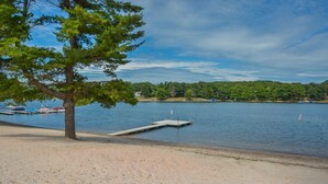 A lakeside view with a dock, sandy beach, and a tree. - Four Hooppole South G6 by Taylor Made Deep Creek (Oakland)